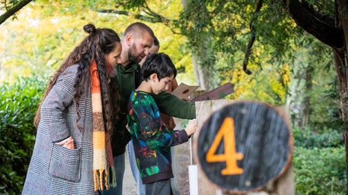 A family try to work out a puzzle in a garden trail.